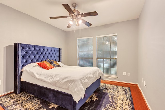 bedroom featuring ceiling fan, baseboards, and wood finished floors