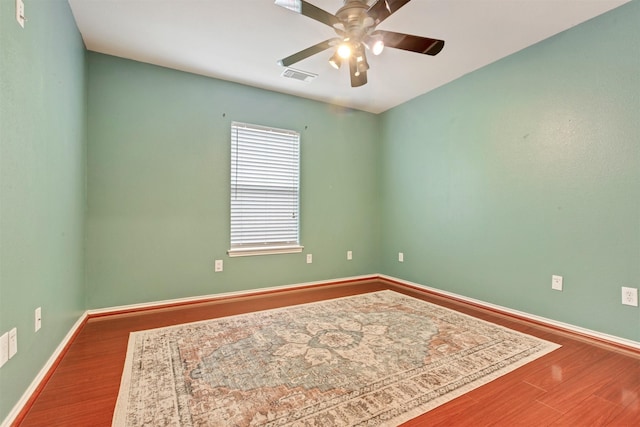 spare room featuring a ceiling fan, wood finished floors, visible vents, and baseboards