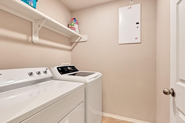 washroom featuring light tile patterned flooring, laundry area, baseboards, electric panel, and washer and clothes dryer