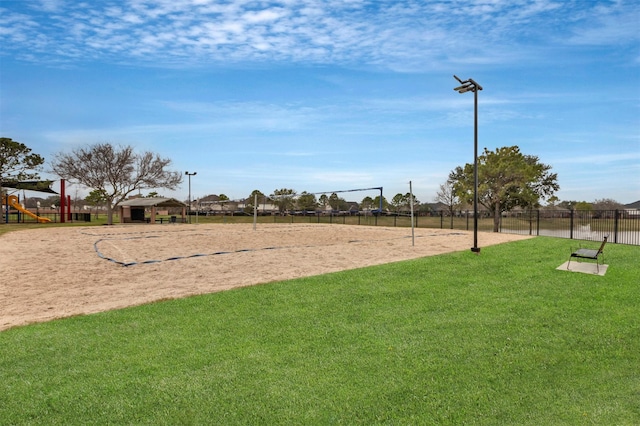 view of community featuring fence, a lawn, and volleyball court