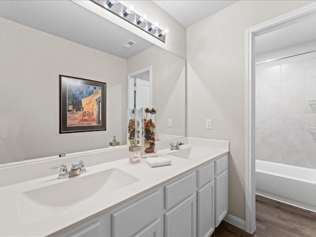 full bath featuring double vanity, visible vents, a sink, and wood finished floors