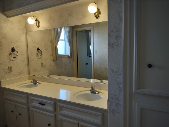 bathroom with double vanity, wallpapered walls, and a sink