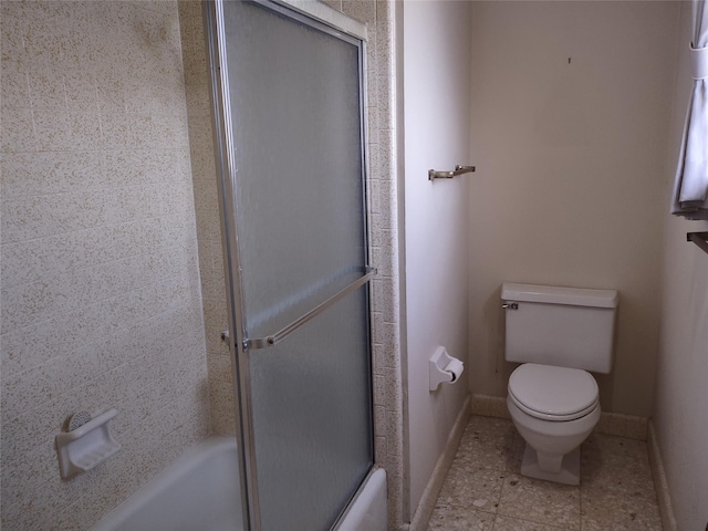 bathroom featuring baseboards, enclosed tub / shower combo, toilet, and tile patterned flooring