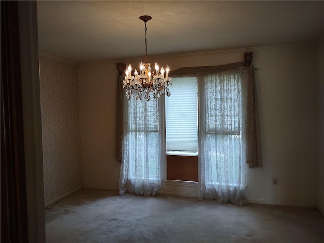 carpeted spare room featuring a chandelier, plenty of natural light, wallpapered walls, and ornamental molding