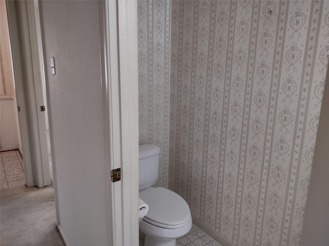 bathroom with tile patterned floors, baseboards, toilet, and wallpapered walls