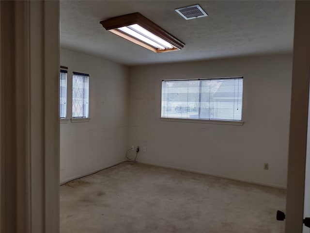 spare room featuring baseboards, visible vents, plenty of natural light, and light carpet