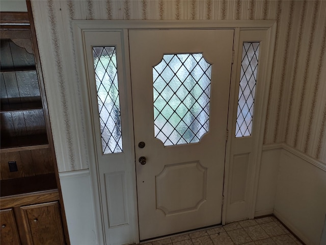 foyer entrance with light tile patterned flooring and wallpapered walls