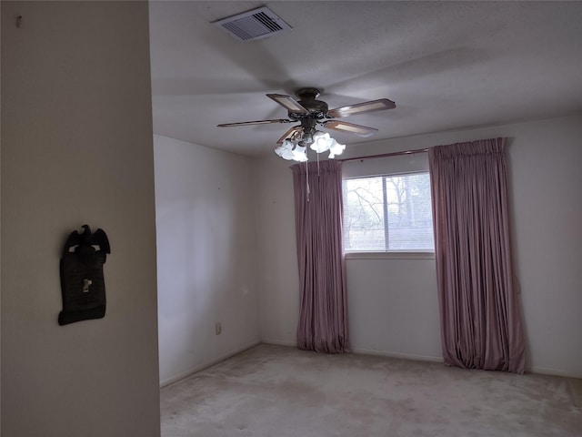 empty room with visible vents, carpet floors, and ceiling fan