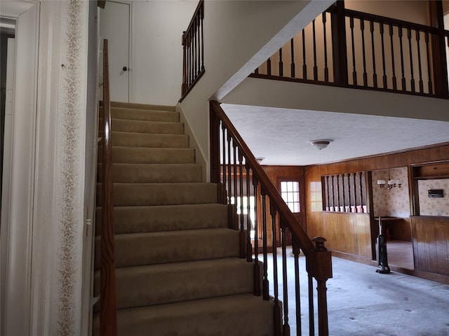 stairway featuring wood walls and a textured ceiling