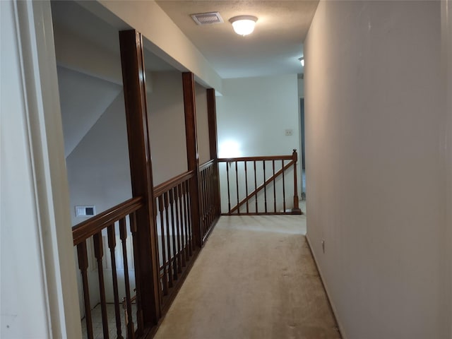 corridor with visible vents, an upstairs landing, and light carpet