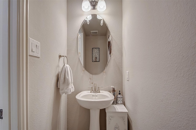 bathroom with a textured wall, a sink, and visible vents