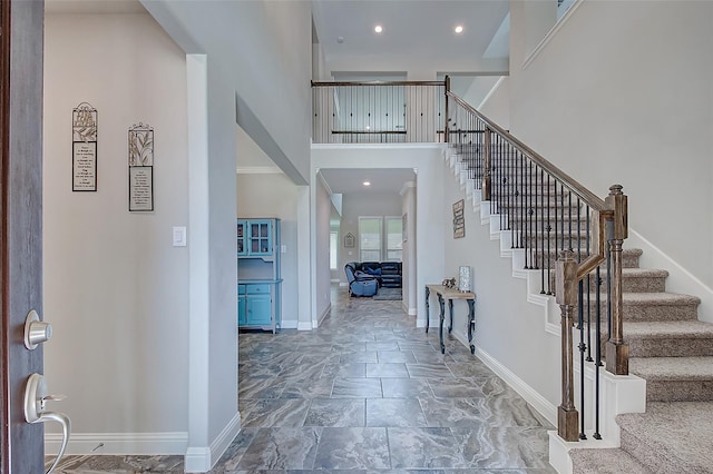 foyer featuring recessed lighting, a towering ceiling, baseboards, and stairs