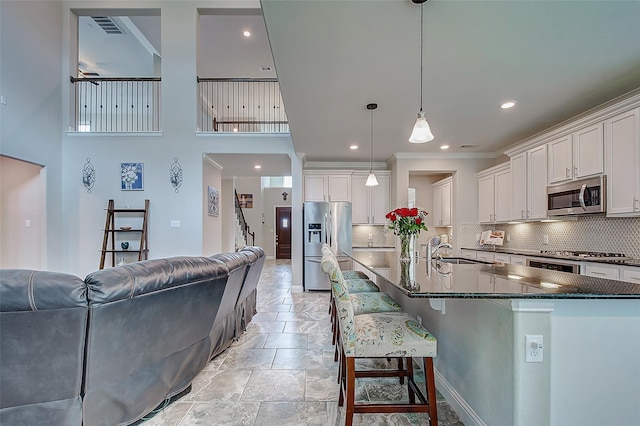 kitchen featuring white cabinetry, appliances with stainless steel finishes, open floor plan, and a sink