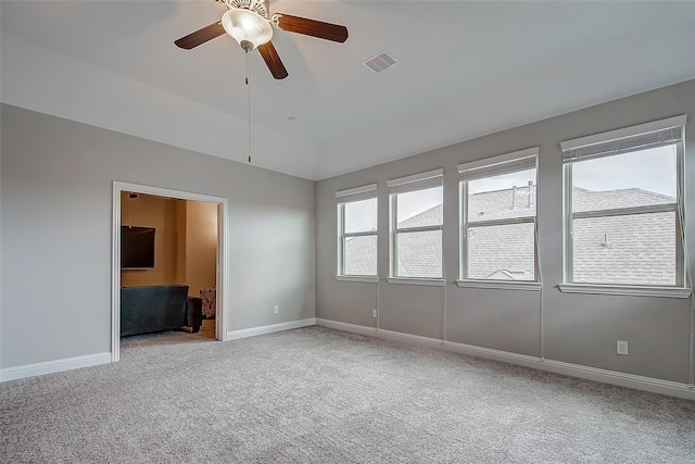 empty room featuring light colored carpet, visible vents, lofted ceiling, and baseboards