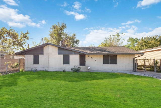 rear view of property featuring brick siding, a lawn, and fence