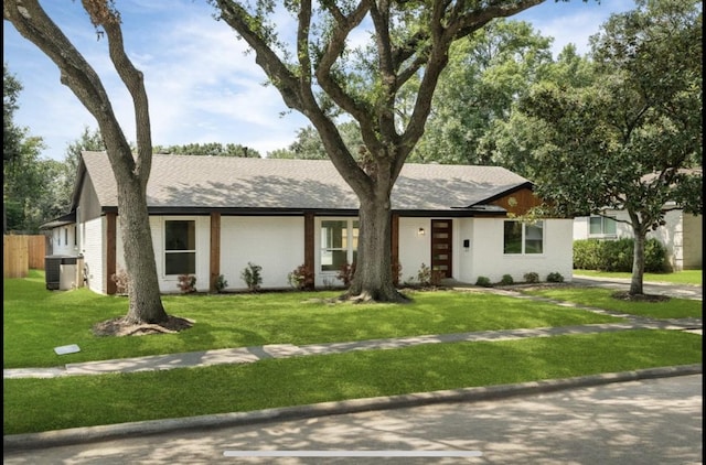 ranch-style home with a front yard, cooling unit, brick siding, and roof with shingles