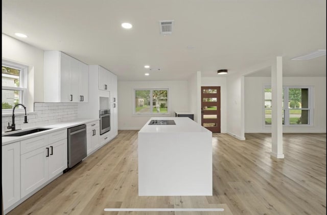 kitchen with a center island, light countertops, appliances with stainless steel finishes, white cabinetry, and a sink