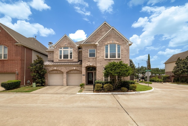 view of front of home with brick siding, concrete driveway, an attached garage, a standing seam roof, and metal roof