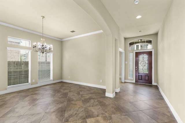 entrance foyer featuring arched walkways, crown molding, baseboards, and an inviting chandelier