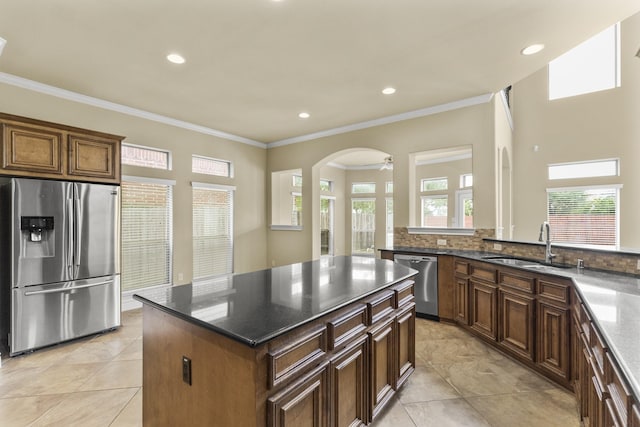 kitchen with appliances with stainless steel finishes, a center island, crown molding, and a sink