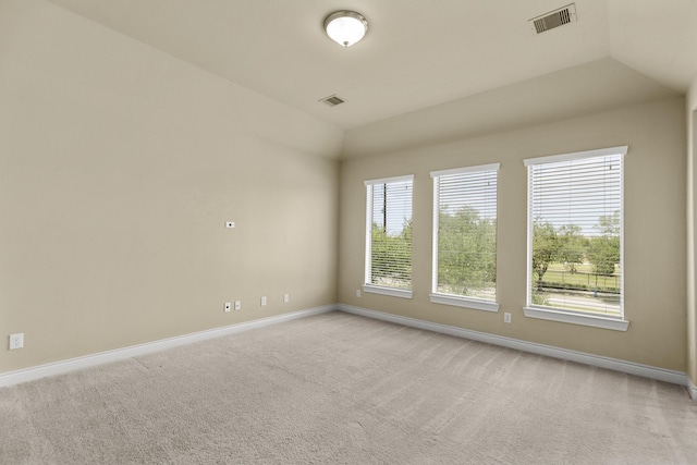 spare room with light carpet, baseboards, visible vents, and lofted ceiling