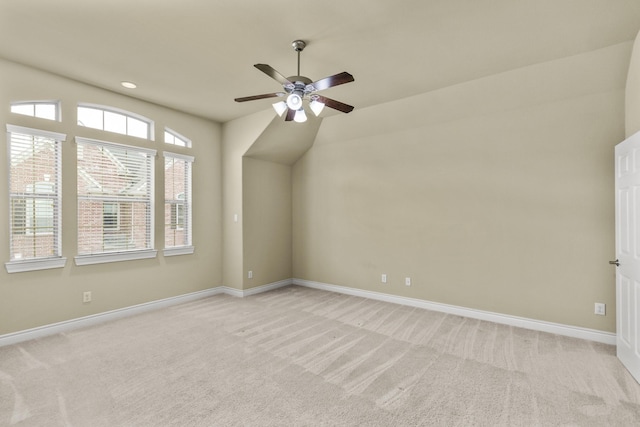 spare room featuring light colored carpet, ceiling fan, and baseboards