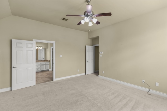 unfurnished bedroom with baseboards, vaulted ceiling, visible vents, and light colored carpet