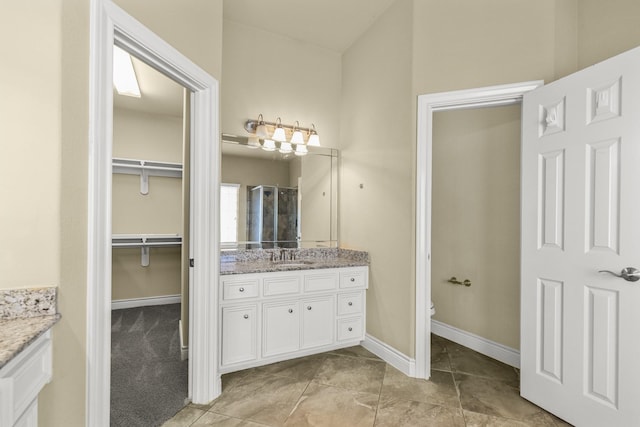 bathroom with baseboards, vanity, toilet, and a spacious closet