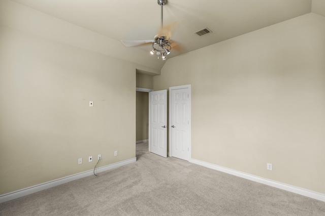 carpeted spare room featuring lofted ceiling, baseboards, visible vents, and a ceiling fan