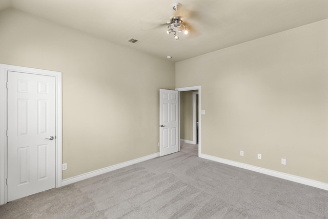 carpeted spare room with ceiling fan, vaulted ceiling, visible vents, and baseboards