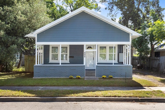 bungalow-style house featuring entry steps, a front lawn, and fence