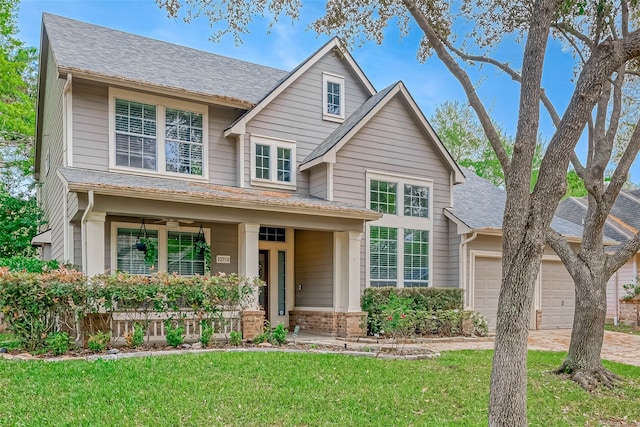 view of front of house with a garage, driveway, a shingled roof, a front lawn, and brick siding