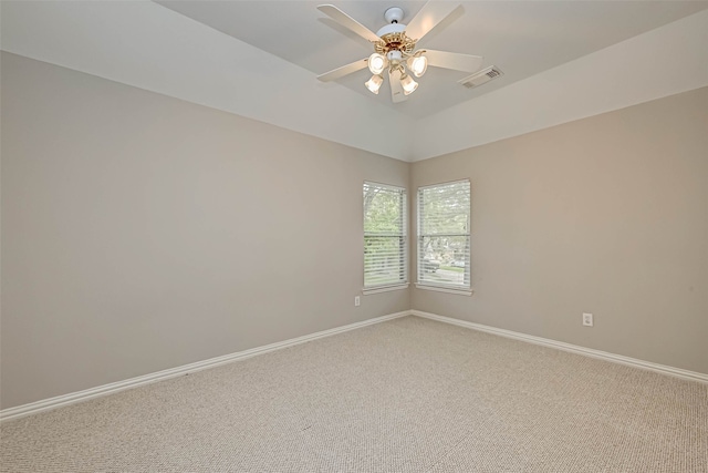 empty room with lofted ceiling, visible vents, a ceiling fan, carpet flooring, and baseboards