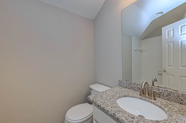 bathroom featuring toilet, vaulted ceiling, vanity, and visible vents