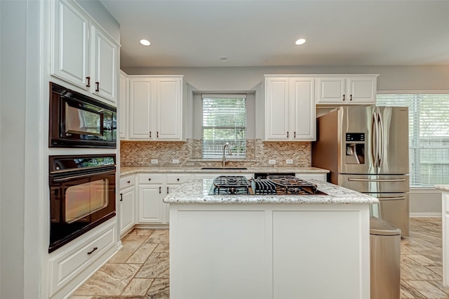 kitchen with a sink, black appliances, a kitchen island, and white cabinets