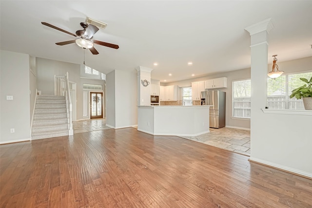 unfurnished living room featuring stairway, ceiling fan, light wood-style flooring, and baseboards