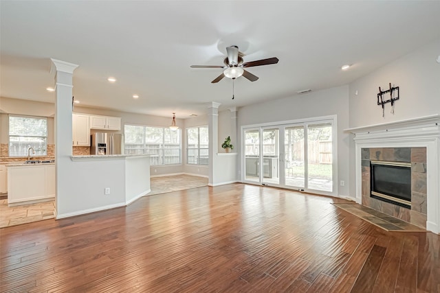 unfurnished living room featuring light wood-style floors, a tile fireplace, and decorative columns