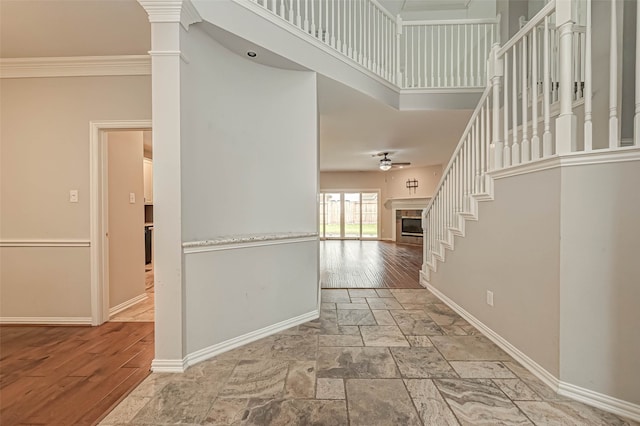 corridor featuring ornamental molding, a towering ceiling, stairway, and baseboards