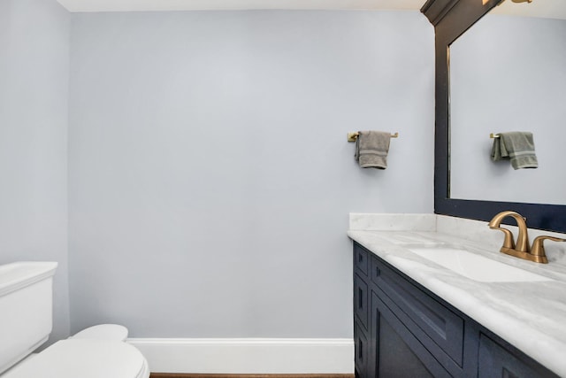 half bathroom featuring baseboards, vanity, and toilet