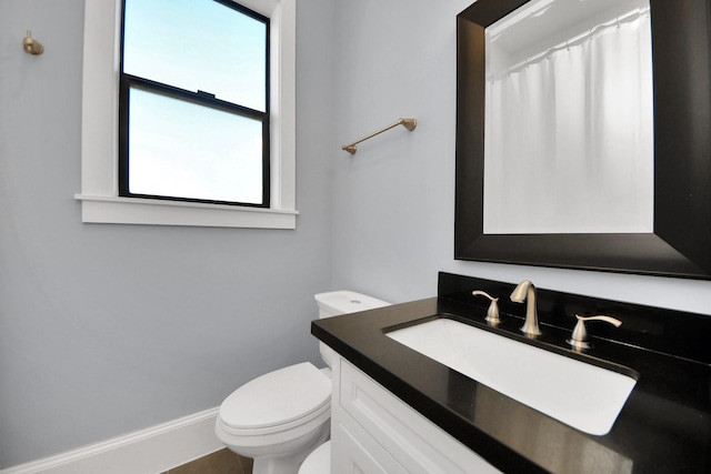 bathroom with toilet, vanity, and baseboards