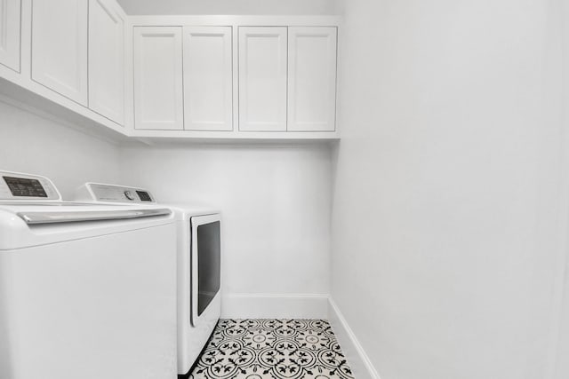 laundry area featuring cabinet space, light tile patterned flooring, baseboards, and washing machine and clothes dryer