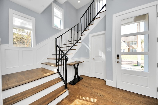 foyer entrance featuring a wainscoted wall, stairs, a wealth of natural light, and wood finished floors