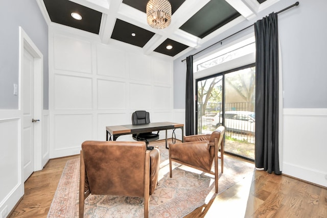 office space featuring coffered ceiling, a decorative wall, and light wood-style flooring