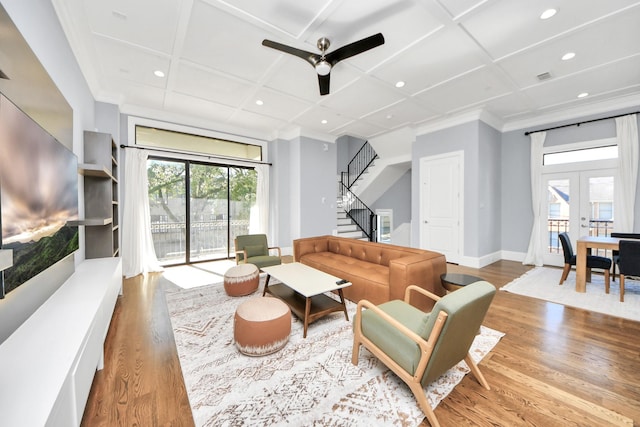 living area with light wood-style floors, french doors, coffered ceiling, and stairs