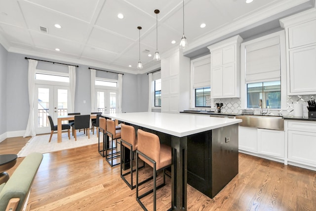 kitchen featuring a sink, french doors, a kitchen island, and white cabinetry