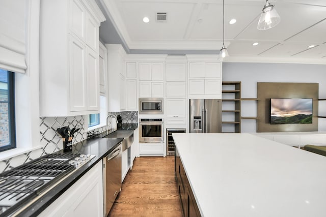 kitchen featuring appliances with stainless steel finishes, a sink, white cabinetry, and pendant lighting