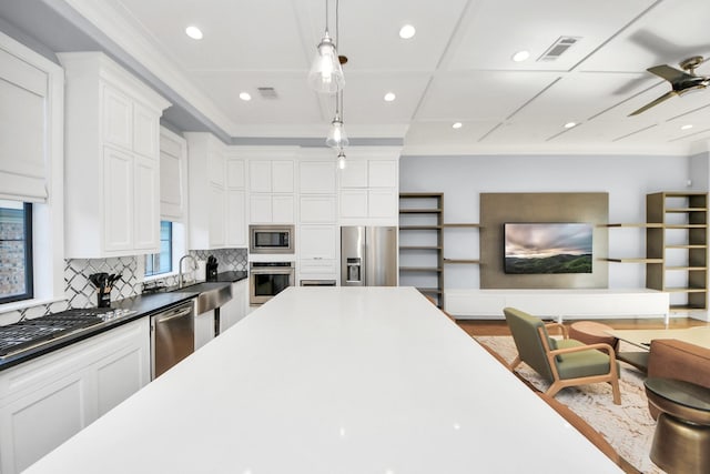 kitchen with light countertops, appliances with stainless steel finishes, white cabinetry, and pendant lighting