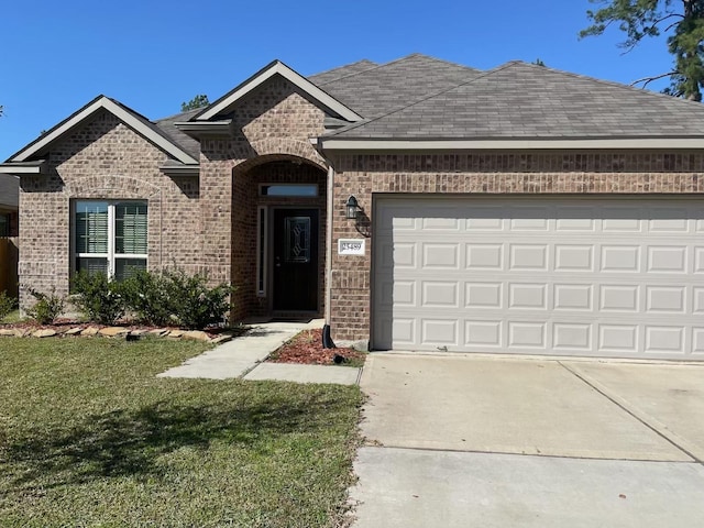 french country inspired facade featuring driveway, brick siding, roof with shingles, an attached garage, and a front yard