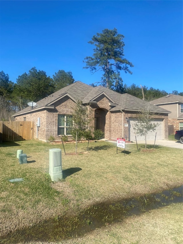 ranch-style home featuring an attached garage, fence, a front lawn, and brick siding