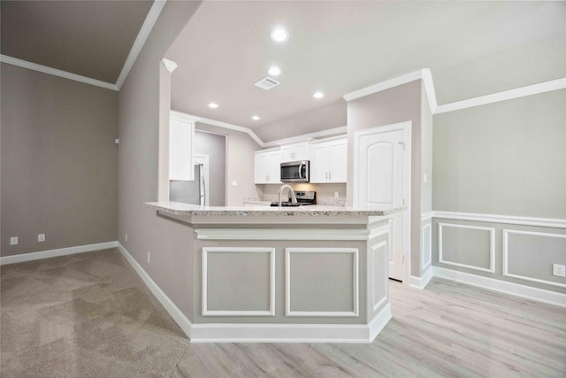 kitchen with visible vents, white cabinets, a peninsula, stainless steel appliances, and crown molding